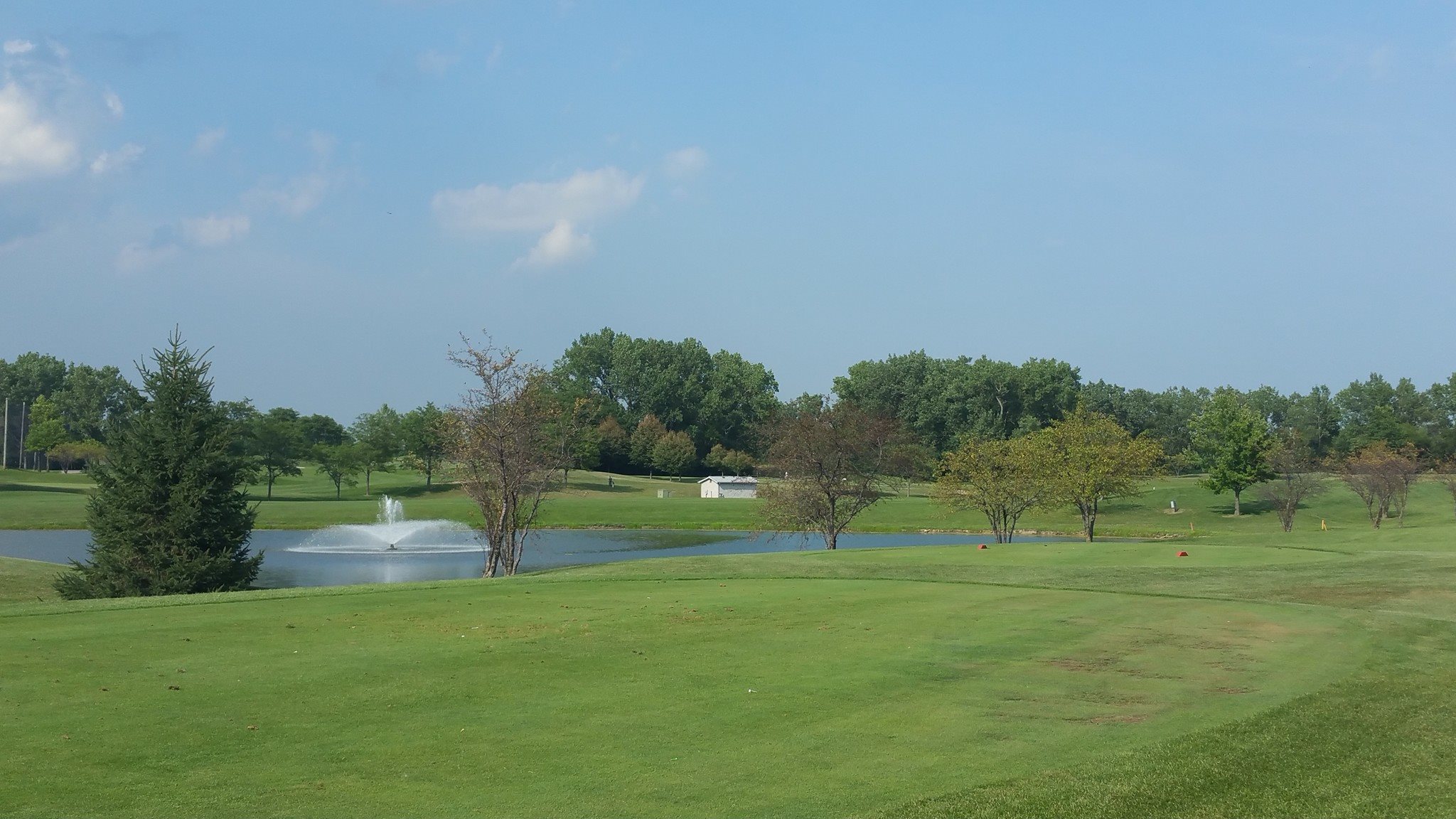 Golf course green with fountain in distance 